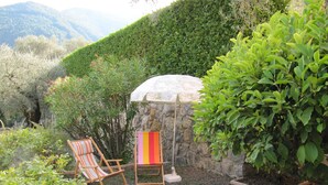 A garden with a stone wall, two striped chairs, and a white umbrella. - Montée St Jean d'Ermi - BREIL-SUR-ROYA (BREIL-SUR-ROYA)
