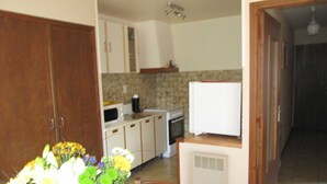 A kitchen with white cabinets, a microwave, a stove, and a refrigerator. - Montée St Jean d'Ermi - BREIL-SUR-ROYA (BREIL-SUR-ROYA)