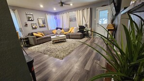 Una sala de estar con un sofá modular, una mesa de centro y un amplio ventanal con cortinas.
