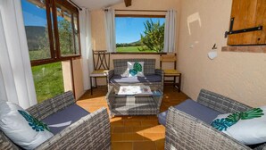 A cozy room with wicker furniture, a view of greenery, and a brick wall. - Laure-Anne - SAINT-AUBAN (SAINT-AUBAN)