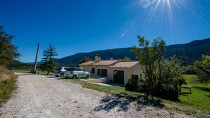 A rural house with a gravel driveway, parked cars, and a clear blue sky. - Laure-Anne - SAINT-AUBAN (SAINT-AUBAN)