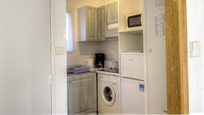 A compact kitchen with a washing machine, a microwave, and a coffee maker.