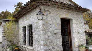 A stone building with a tiled roof, a wooden door, and a lantern.