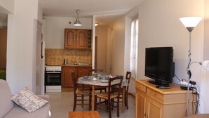 A compact living space with a dining area, kitchenette, and a TV on a wooden cabinet.