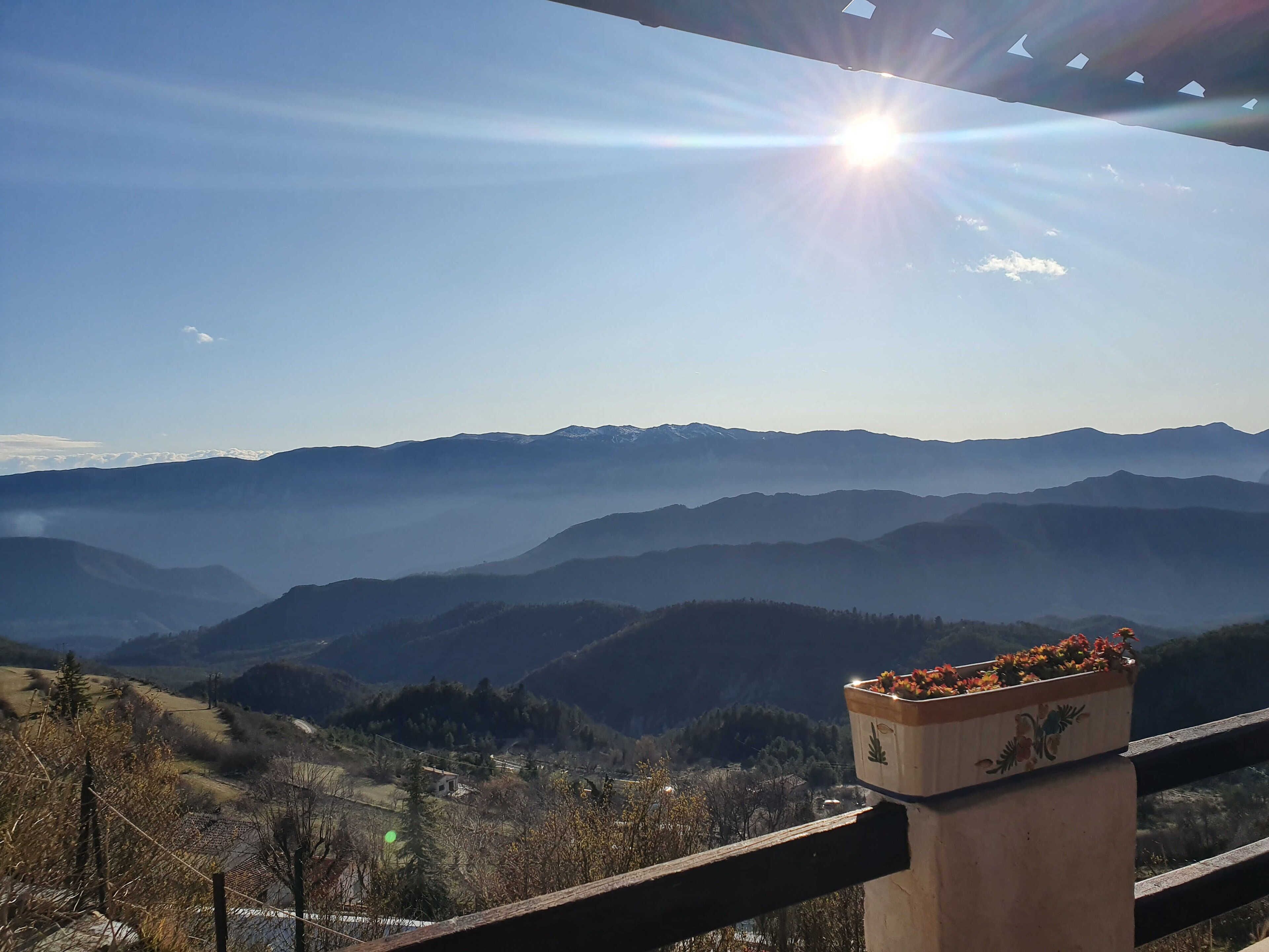 Un paysage montagneux, avec un ciel dégagé et un soleil éclatant.
