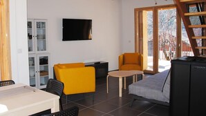 A living room with a sofa, a yellow armchair, a television, and a cabinet. - La Grange du Lavoir - VENANSON (VENANSON)
