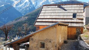 A rustic mountain cabin with a sloped roof, stone walls, and a small wooden door. - La Grange du Lavoir - VENANSON (VENANSON)