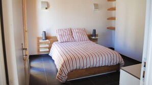 A bedroom with a bed, bedside tables, and a built-in shelf unit. - La Grange du Lavoir - VENANSON (VENANSON)