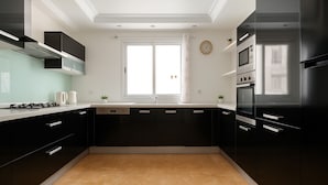A modern kitchen with black cabinets, a stainless steel refrigerator, and a window with a view. - Spacieux Appartement à Hydra (Timokten)