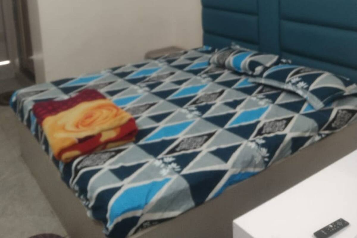 Un dormitorio con una cama, una mesita de noche y un aire acondicionado instalado en la pared.