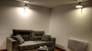 A modern living room with a grey sofa, two side tables, and a wall-mounted radiator.