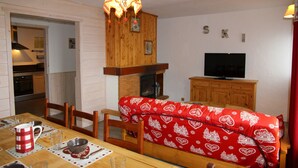 A cozy living room with a red patterned sofa, wooden cabinets, a television, and a fireplace.