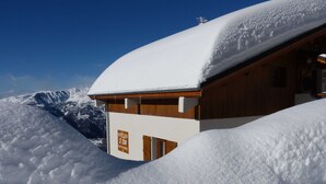 A snow-covered mountain lodge with a wooden exterior and a sign indicating it is Villa St. Jean.