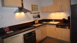 A compact kitchen with wooden cabinets, a stainless steel range hood, a sink, and a dishwasher.