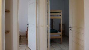 A room with a bunk bed, a chair, and a door leading to another room.