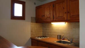 A kitchen with wooden cabinets, a gas stove, a sink, and a window.