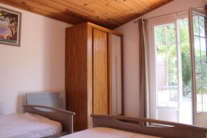 A bedroom with a wooden ceiling, a bed, a wardrobe, and a window with curtains. - La Ferme Riola - Gîte n°6180 (Contes)