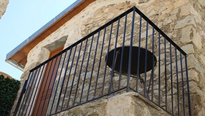 A stone building with a metal balcony railing and a circular window.