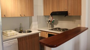 A compact kitchen with wooden cabinets, a Bosch dishwasher, a sink, and a stove.