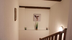 A staircase with a wooden handrail, a framed picture on the wall, and a small potted plant on the landing.