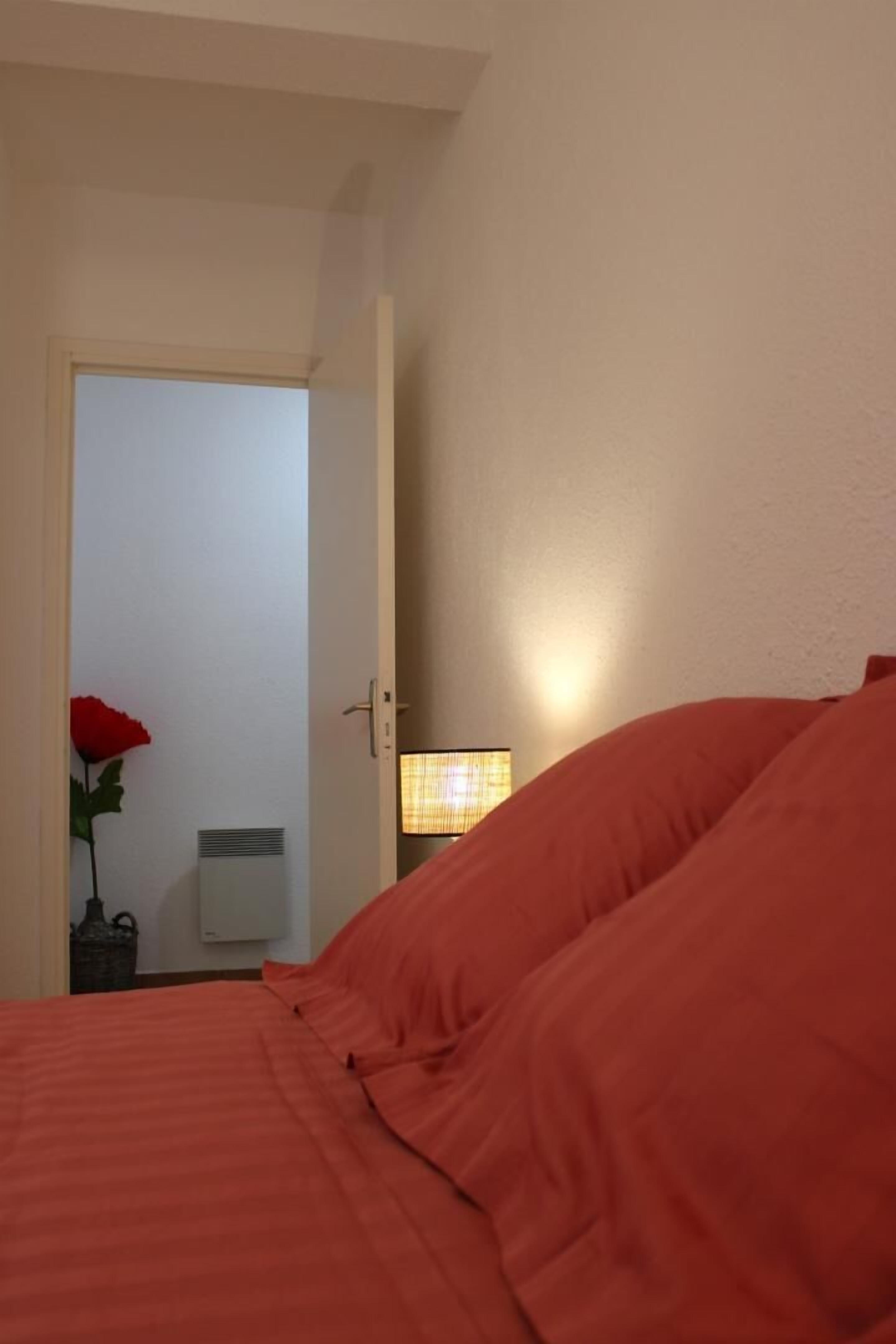 Une chambre d’hôtel avec un lit, une table de chevet avec une lampe et une porte donnant sur une autre pièce.
