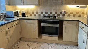 A modern kitchen with light wood cabinets, a gas stove, a microwave, and a toaster. - Central 2-bed Apartment - Sleeps 5 & Free Parking (Derby)
