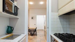 Ett kök med en spis, en mikrovågsugn och en matplats med stolar och ett bord.