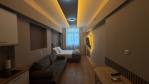 A modern hotel room with a sofa, a bed, a TV, and a small table. - Monastiraki 303 Superhost Hub (Athens)