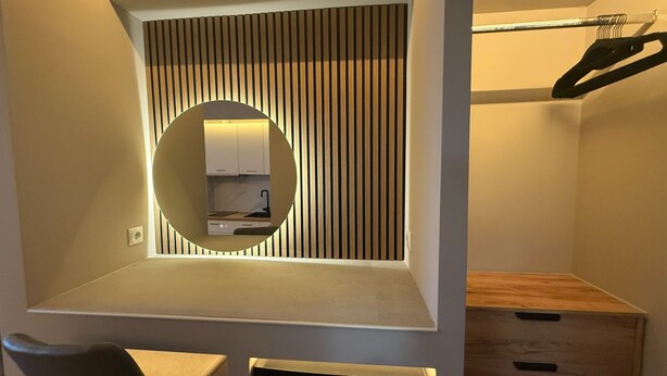 A modern, compact bedroom with a built-in wardrobe, a circular mirror, and a small kitchenette. - Monastiraki 303 Superhost Hub (Athens)