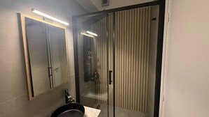 A modern bathroom with a glass shower enclosure, a sink, and a mirror. - Monastiraki 303 Superhost Hub (Athens)