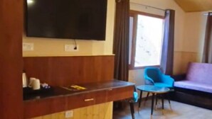 Una habitación con mostrador de madera, televisor montado en la pared, una silla azul y un sofá morado.