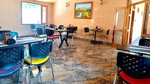 Un comedor con mesas y sillas, un cuadro en la pared y un techo de madera.