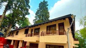 Un edificio de dos pisos con balcones, fachada roja y cielo despejado.