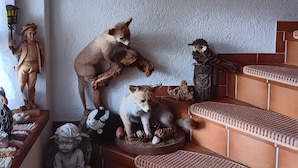 Una habitació amb una escala, un penjoll de macramè a la paret i diverses figures d'animals.