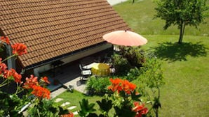 Una casa amb teulada de rajola, garatge i jardí amb flors vermelles.