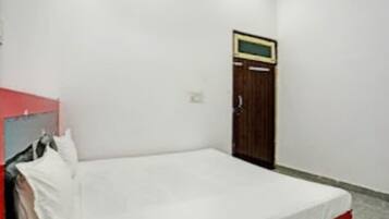 Una habitación pequeña con cama individual, un armario de madera y un televisor fijado a la pared.