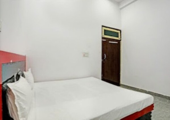 Una habitación pequeña con cama individual, un armario de madera y un televisor fijado a la pared.