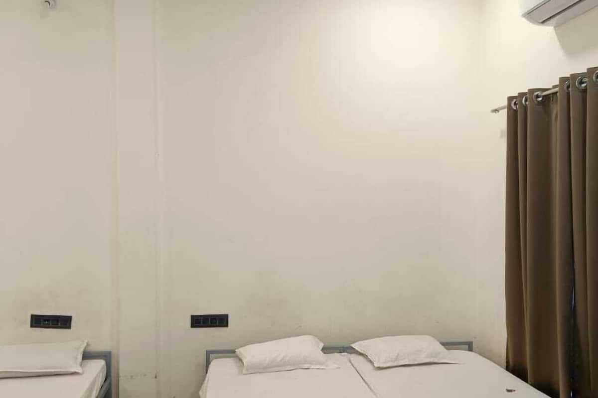 A room with two beds, a ceiling fan, an air conditioner, and a curtain.