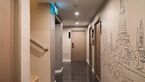 A hotel hallway with a marble floor, a handrail, and a wall mural of a cityscape. - Ralph Poshtel Pratunam (Bangkok)