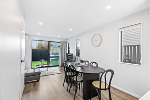 A dining area with a round table, chairs, and a view of the outdoors. - Stylish 4BR Townhouse in Suburbs by Zodiak (Auckland)