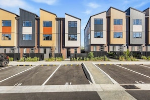 A row of modern multi-story residential buildings with numbered parking spaces. - Stylish 4BR Townhouse in Suburbs by Zodiak (Auckland)