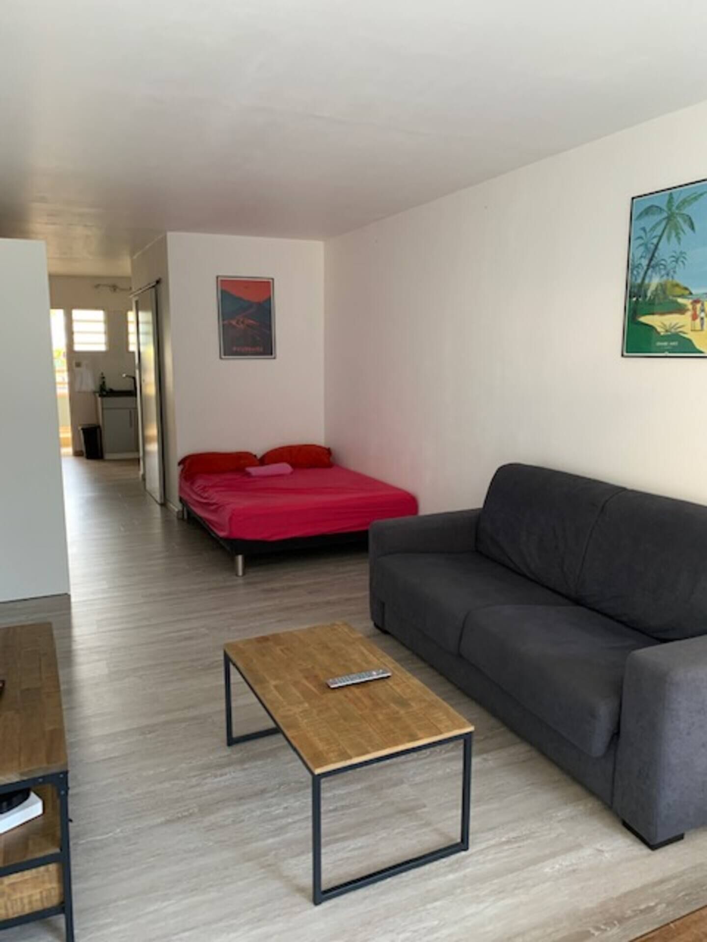 A living room with a grey sofa, a red bed, and a wooden coffee table.