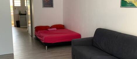 A living room with a grey sofa, a red bed, and a wooden coffee table.
