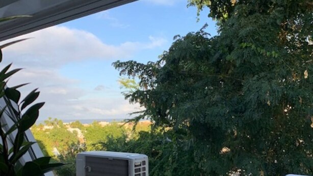 Ein Balkon mit einem Holztisch, einem Blumentopf und zwei Klimaanlagen.