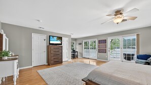A bedroom with a bed, a dresser, a TV, and a ceiling fan.