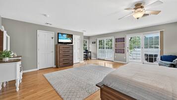 A bedroom with a bed, a dresser, a TV, and a ceiling fan.