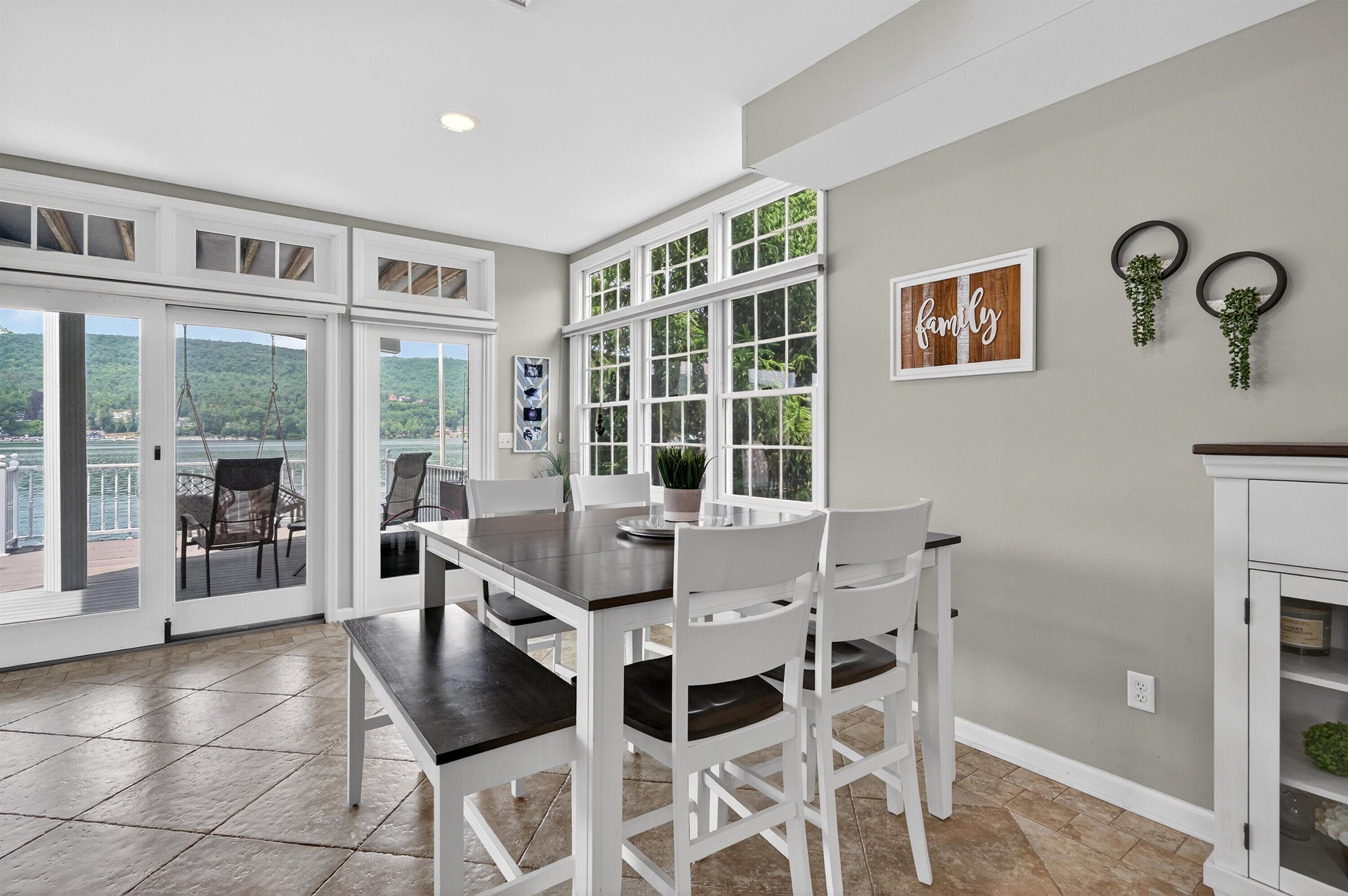 A dining area with a table and chairs, large windows, and a view of a balcony.
