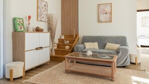 A living room with a grey sofa, a glass coffee table, a white cabinet, and a staircase with wooden railings. - New house in Sarlat with garden and terrace (Sarlat-la-Canéda)