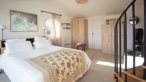 A bedroom with a large bed, a wooden staircase, a desk, and a wardrobe. - Carqueiranne: Charming Villa with Pool, Sea View, for 8 Guests (Carqueiranne)