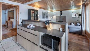Una cocina moderna con microondas integrado, armarios de madera y una encimera con un bloque de cuchillos.